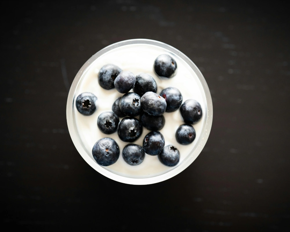 Bowl of Greek yogurt topped with fresh berries and honey